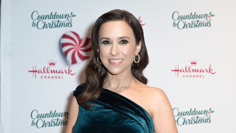 A woman stands in front of a background that says countdown to christmas