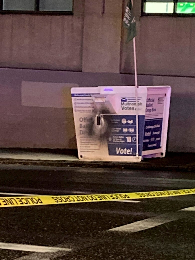 A white ballot box shown with a hole burned in the side.