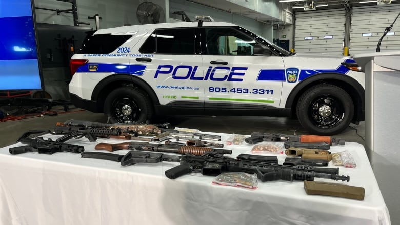 Photo of guns on a table next to a police car