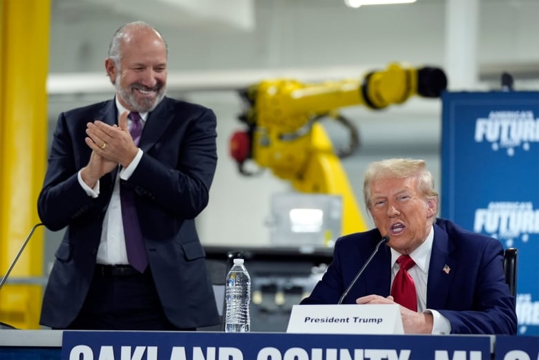 Republican presidential nominee former President Donald Trump arrives for a roundtable, Friday, Oct. 18, 2024, in Auburn Hills, Mich.,as Howard Lutnick, CEO of Cantor Fitzgerald applauds. (AP Photo/Evan Vucci)