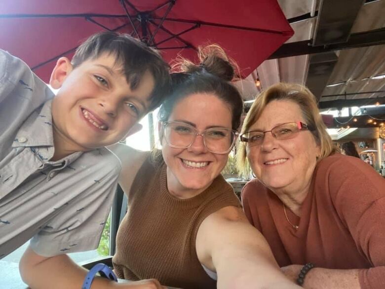 Two woman and a young boy smile in a selfie.