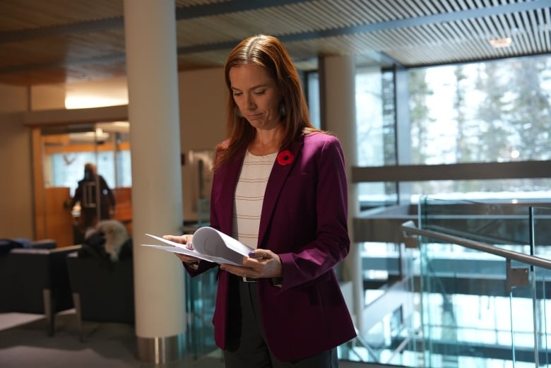 A woman stands looking at a document.