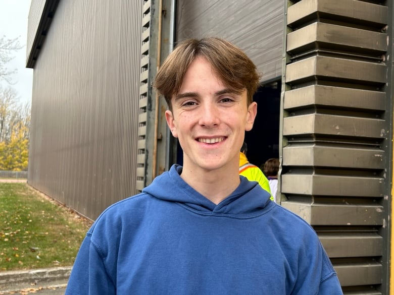 A white boy with brown hair, wearing a blue hoodie.