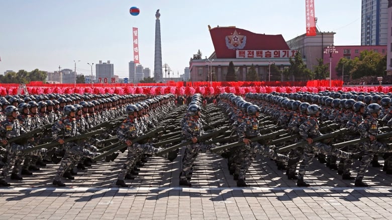 Uniformed North Korean soldiers carrying weapons march in formation. 