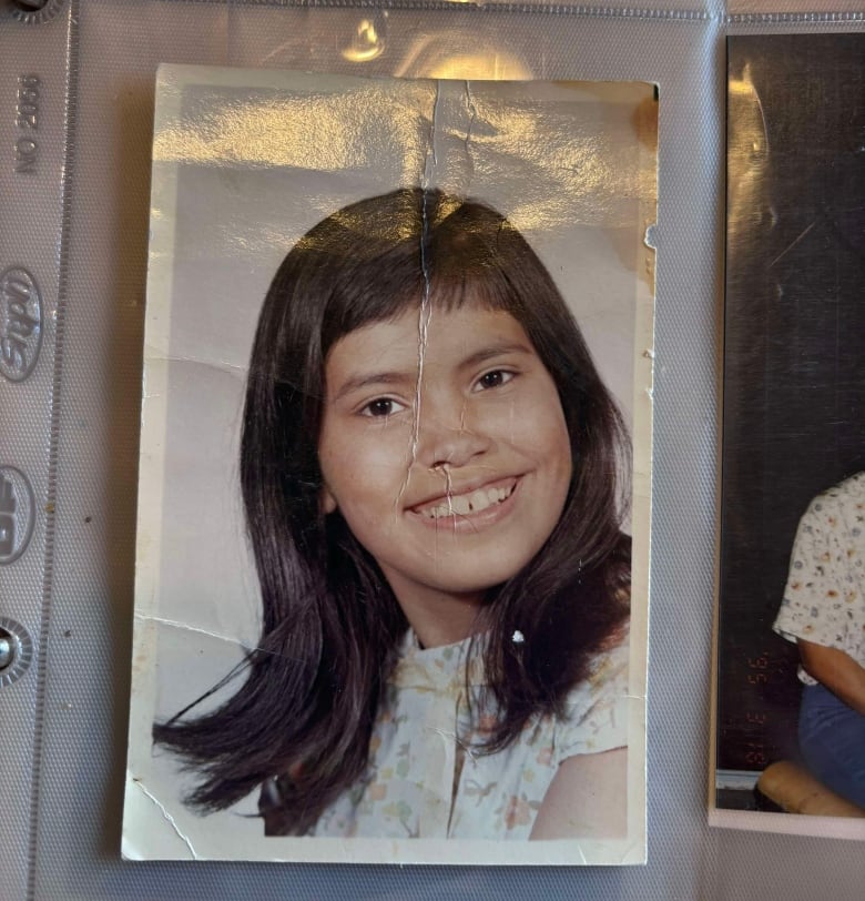 A smiling Indigenous child is seen in a photo in an album.