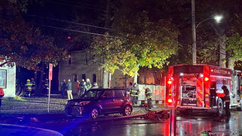 A fire truck parked by a curb on a city street at night.