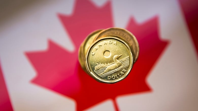 A Canadian dollar coin is shown against a Canadian flag backdrop.