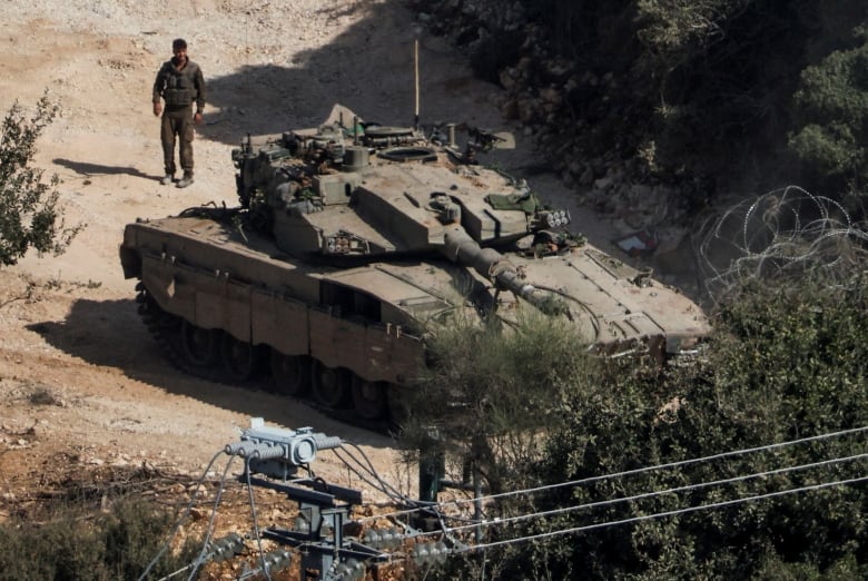 A soldier stands next to a tank.