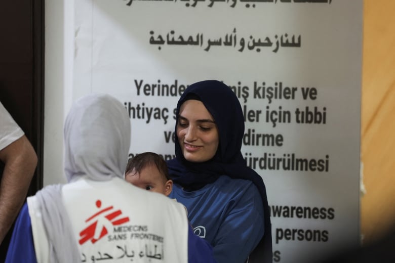 A health worker holds a baby in her arms.