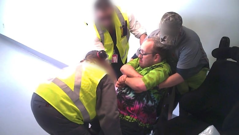 A man being lifted into a chair but two airline staff members.