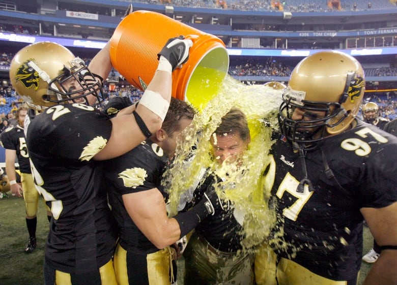 Football players pour gatorade over the head of a coach