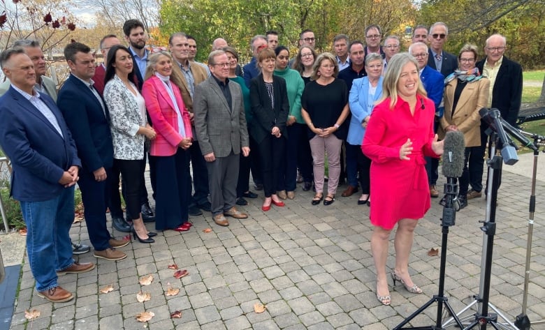 A woman standing at a microphone with a group of people standing behind her.