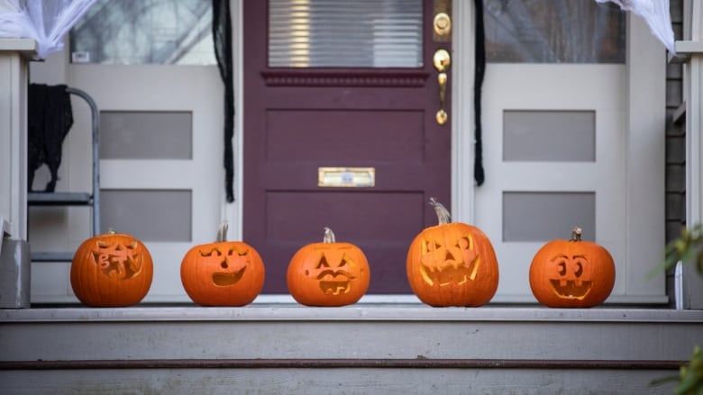 Five jack-o-lanterns are pictured sitting on a doorstep. 