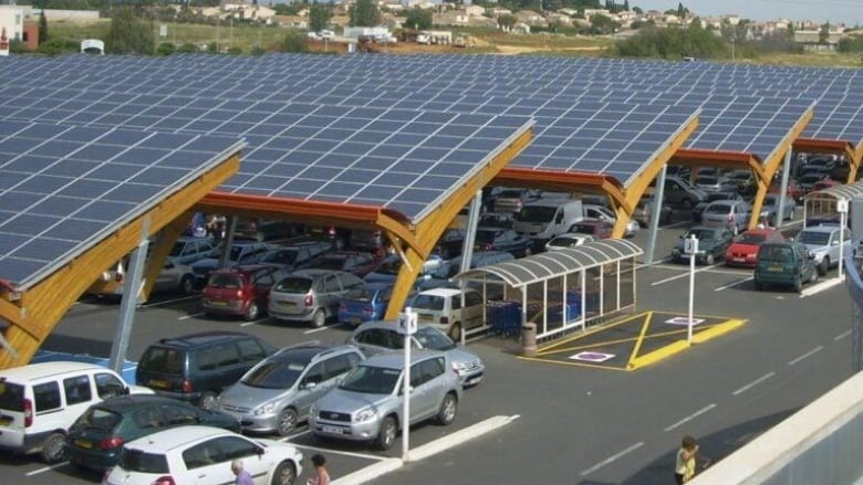 Parked cars covered with solar panel structures.