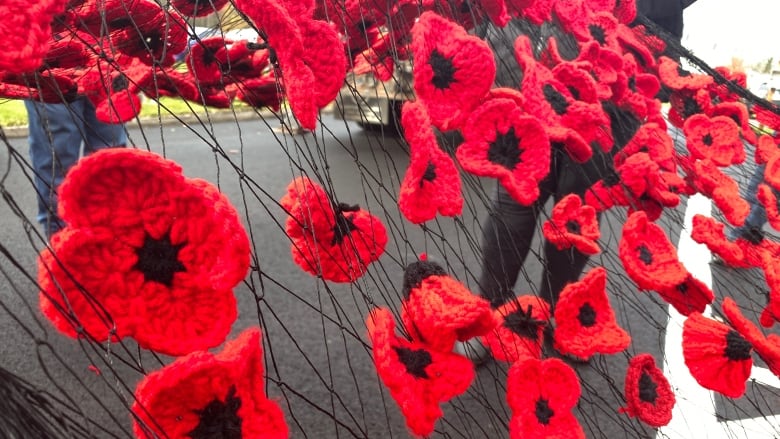 Knitted poppies attached to a mesh framework. 