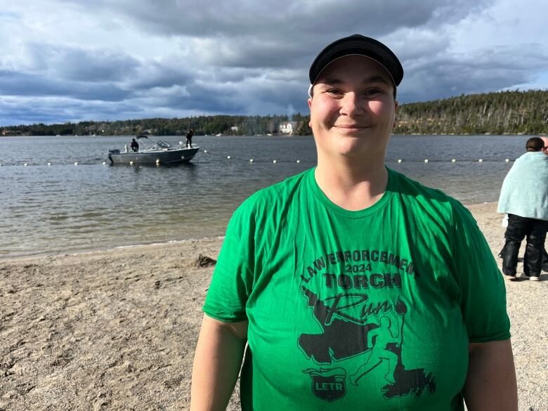 A woman standing on a beach near the shoreline.