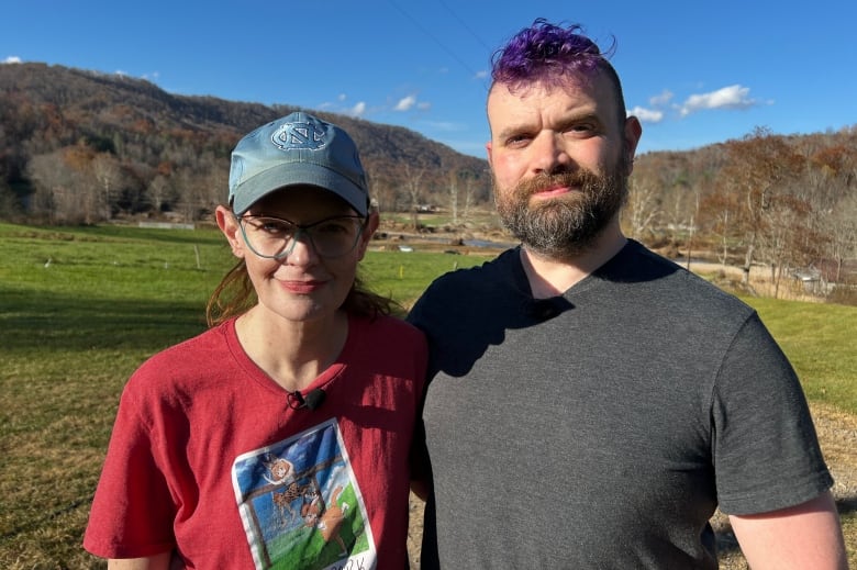 Two people standing in a field embrace while posing for a photograph.