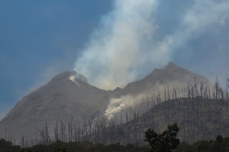 A mountain is shown, with smoke rising all around it.