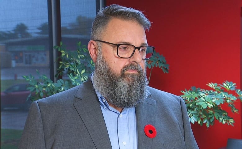 Man with long beard wearing poppy.