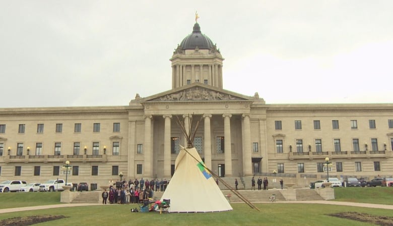 A tipi is seen in front of a building.