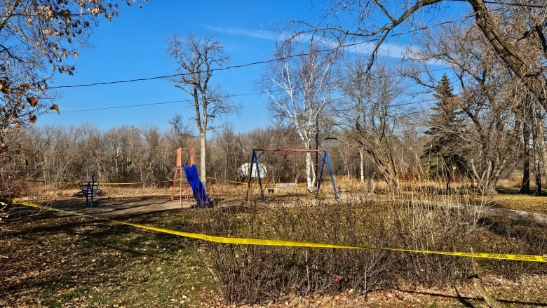 Yellow tape surrounds a park with tall grass.