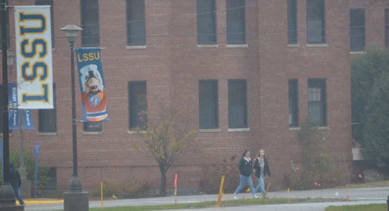 students walking on campus with an LSSU banner hanging nearby