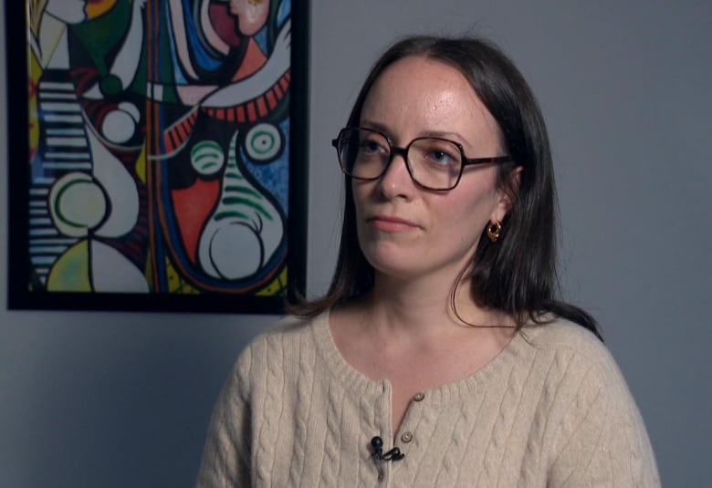 A woman with a painting behind her