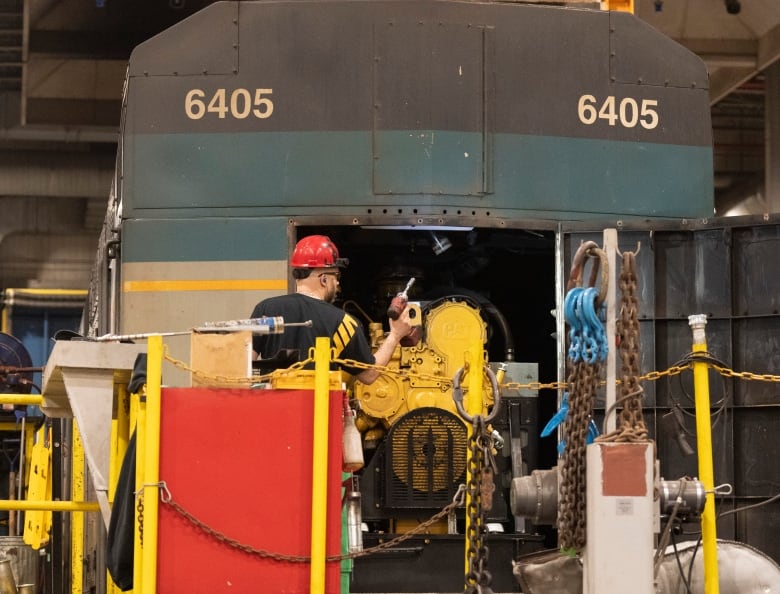 Employees work on a locomotive inside the Via Rail Canada Maintenance Centre in Montreal, Thursday, Feb. 22, 2024.