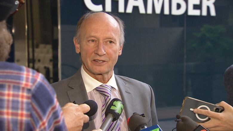 A man stands in front of a group of reporters.