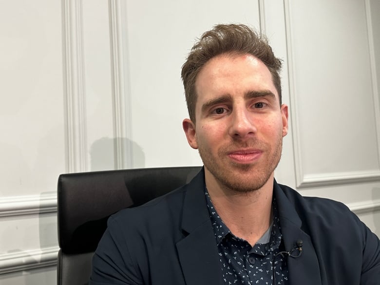 A man in a suit sits by a table.