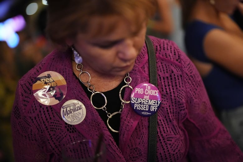 A woman in a purple cardigan wearing several  pro-choice buttons