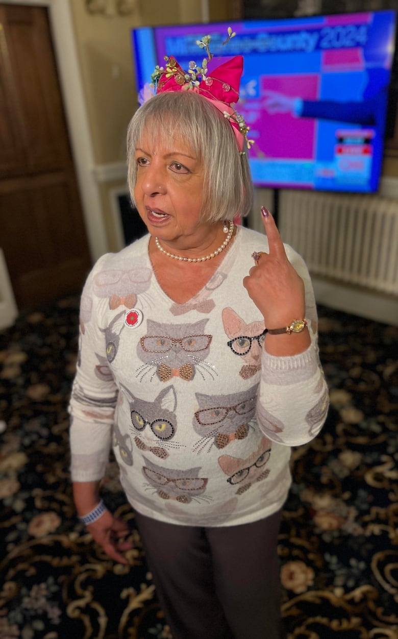 A lady in pink cat ears watches the presidential race.