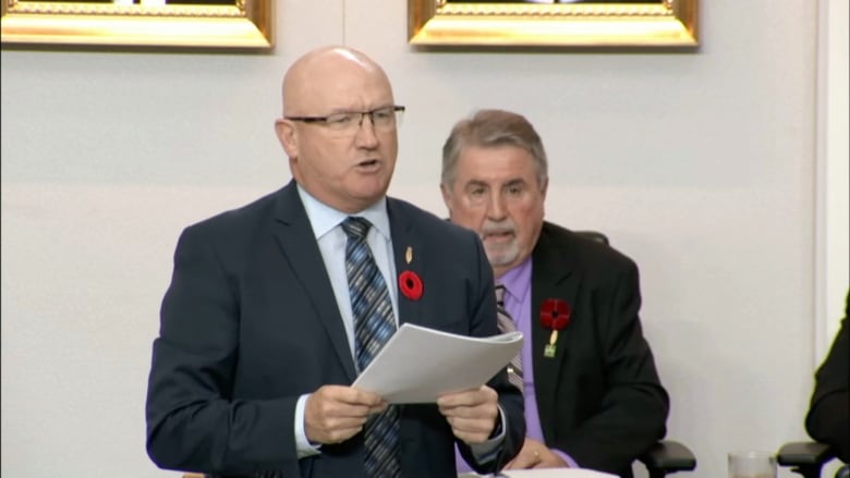 Man in suit reading off paper