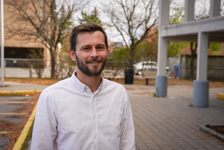 a man smiling standing outside of a community centre.