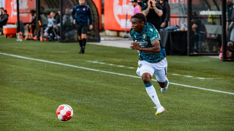 A men's soccer player runs with the ball.