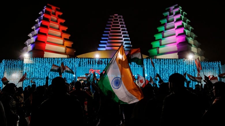 Holding flags, Bramptons Hindu community members hold a rally at the Hindu Sabha temple whose structures are lit at night.