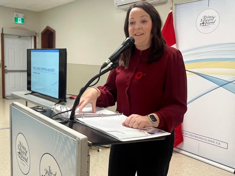 A woman stands behind a podium speaking.