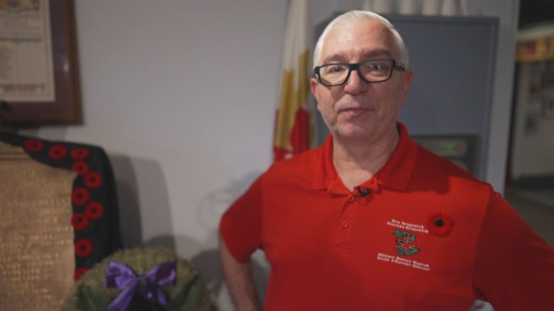 A man wearing a red shirt and a poppy