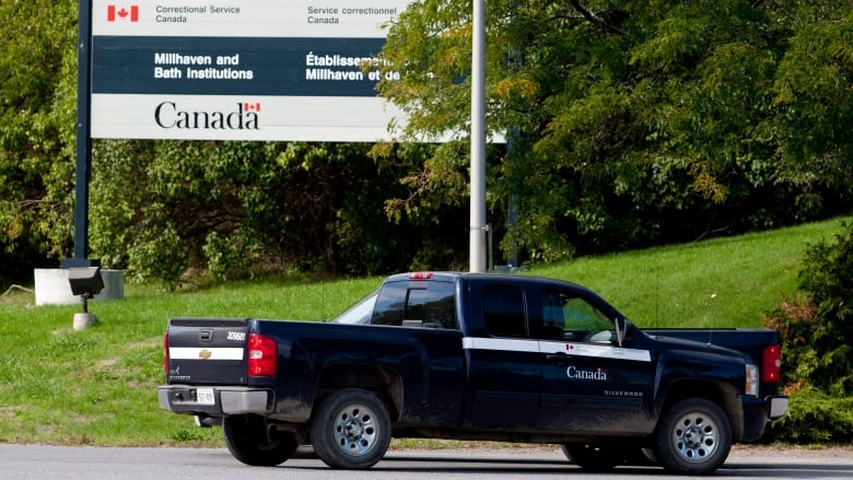 Two dark trucks at the entrance to a prison.