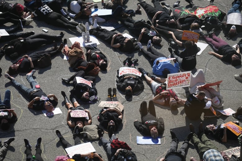 Supporters and harm reduction workers stage a die-in outside of the Ontario legislature in Toronto on Monday , October 21, 2024, as groups gather to protest against the Ontario government's proposal to close consumption treatment sites.THE CANADIAN PRESS/Chris Young