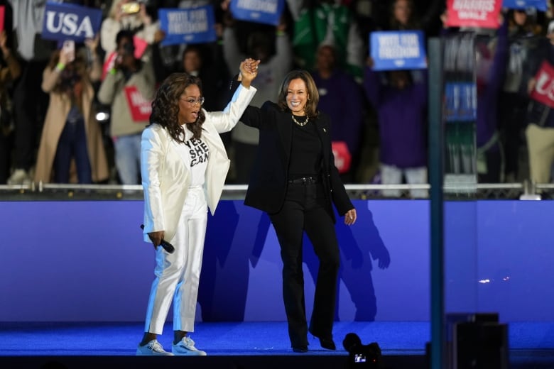 Oprah Winfrey holds hands with Democratic presidential nominee Vice President Kamala Harris after introducing her to speak during a campaign rally outside the Philadelphia Museum of Art, Monday, Nov. 4, 2024, in Philadelphia. 