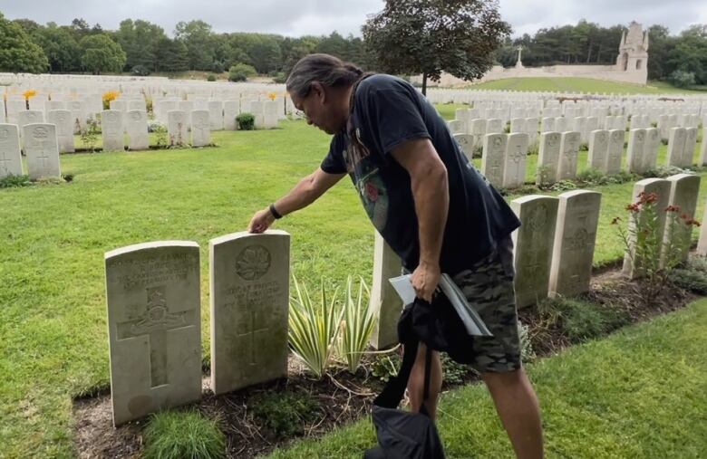 A places a penny on the top of a gravestone