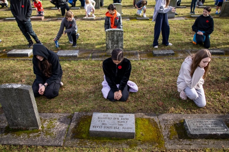 Children are pictured kneeling at gravestones.