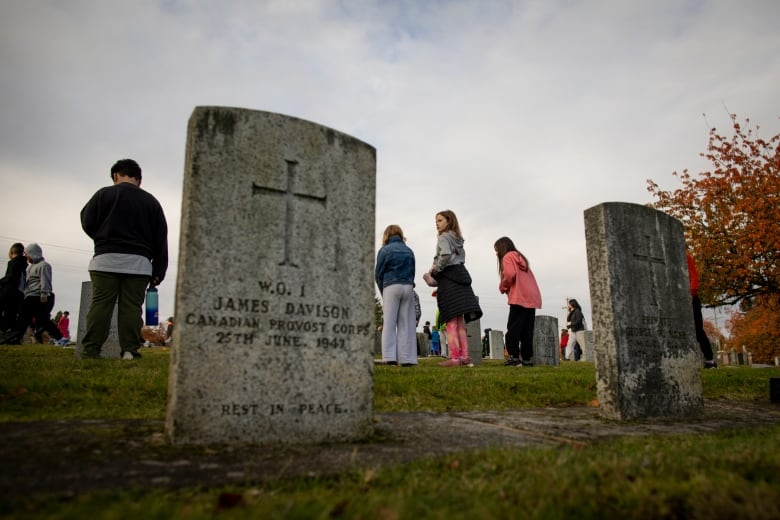 The gravestone of James Davison is pictured, with children at other gravestones in the background.