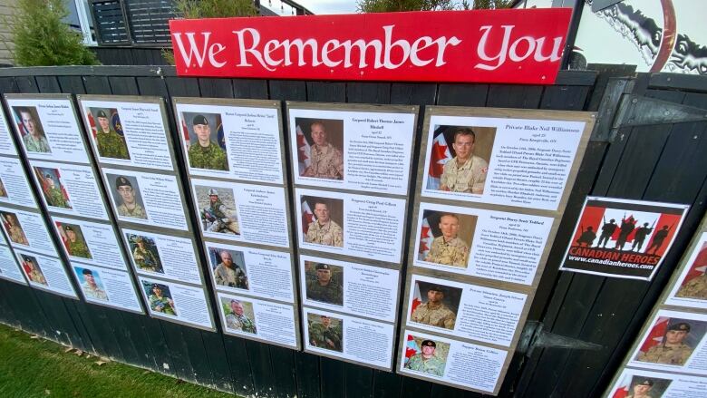 A fence that is lined with photographs and biographies of veteran soldiers. 