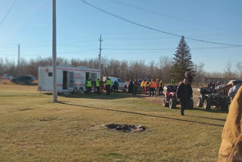 A group of people are standing besides a white truck. 