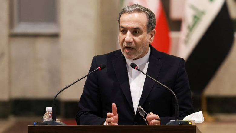 A person gestures while speaking at a lectern.