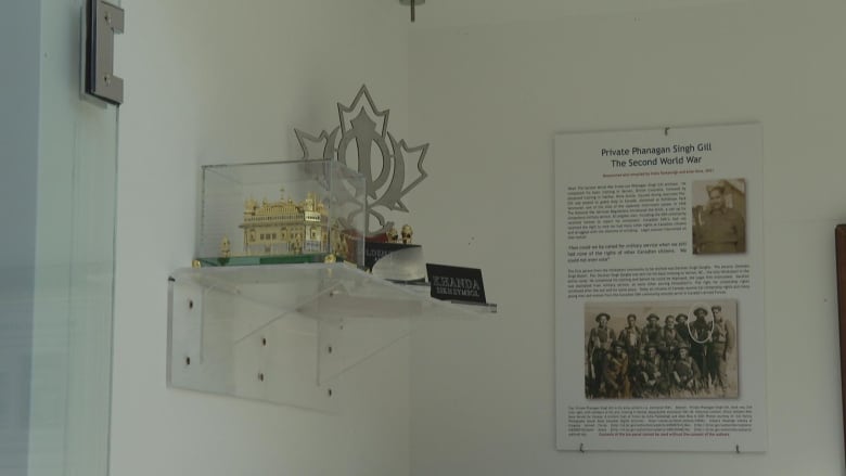 A small statue of a gold building and a trophy shaped like a maple leaf sit on a shelf, next to them is a plaque.