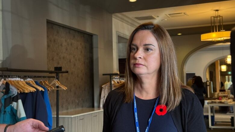 A woman wearing blue with a red poppy pin.