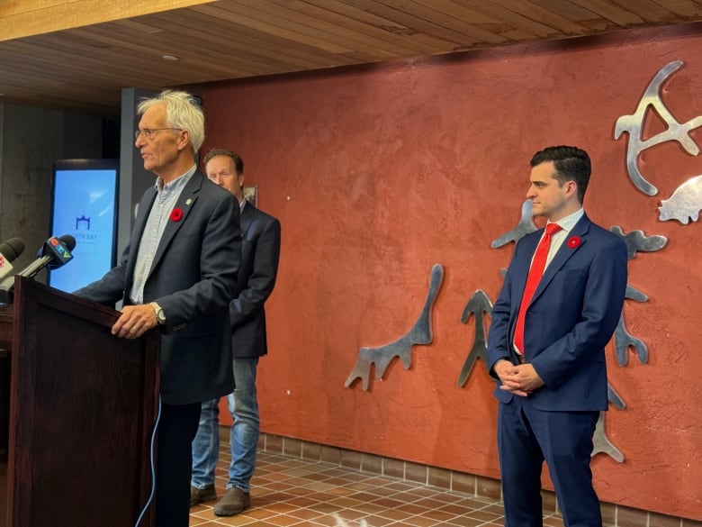 Three men stand behind a podium